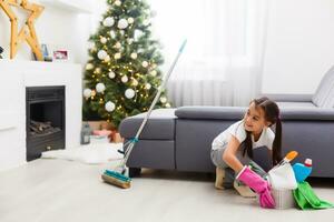 little girl cleaning after christmas on the background of Christmas lights. photo