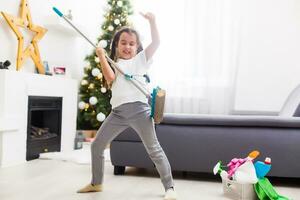 little girl cleaning after christmas on the background of Christmas lights. photo