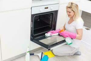 The girl on kitchen wipes an oven photo