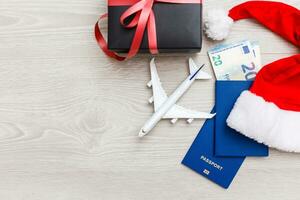 composition with Christmas decorations, toy airplane and passport on white background, space for text. Winter vacation photo