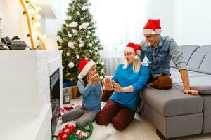 family, christmas, x-mas, winter, happiness and people concept - smiling family in santa helper hats with many gift boxes and bengal lights photo