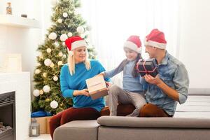 family, christmas, x-mas, winter, happiness and people concept - smiling family in santa helper hats with many gift boxes and bengal lights photo