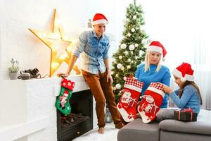 family, christmas, x-mas, winter, happiness and people concept - smiling family in santa helper hats with many gift boxes and bengal lights photo