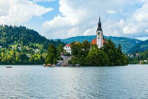 Beautiful cathedral in the middle of the lake surrounded by colourful trees photo