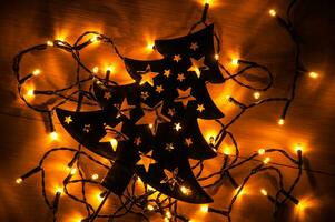 Black Christmas tree on the wooden background with small yellow Christmas lights photo