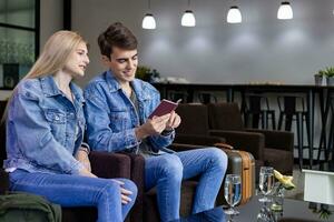 Caucasian traveller couple is looking at visa permit in the passport while waiting in airline business departure lounge terminal waiting for boarding airplane photo