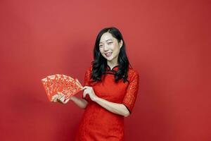 Asian woman holding red money fortune envelope blessing Chinese word which means, May you have great luck and great profit, isolated on red background for Chinese New Year celebration photo