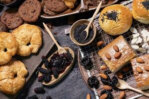 mesa parte superior ver de orgánico rústico estilo panadería con todo grano bollo, un pan y galletas con varios baya y nuez para hecho en casa sano Pastelería y tradicional horneando un pan concepto foto