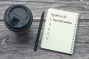 My goals in life list on notepad with pen and coffee on wooden desk. photo