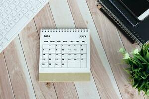 White July 2024 calendar on office wooden desk. photo