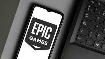 Buenos Aires, Argentina, 2023 - Epic Games logo is displayed on a smartphone screen with a notebook on the side photo