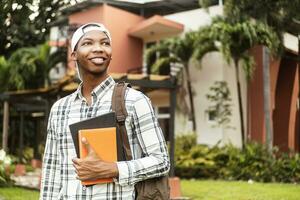 Confident student wearing a cap and holding books. photo