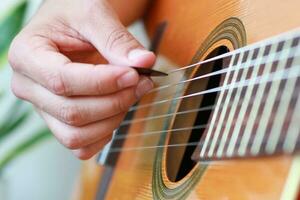 de cerca de jugando un guitarra con un elegir. foto