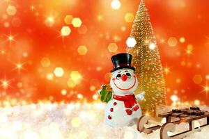 Christmas banner with bokeh and place for text. Snowman with wooden sleigh and Christmas tree on artificial snow with red background photo
