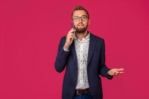 Studio shot of attractive brunette business man with glasses, in casual shirt, stylish black jacket talking on the cell phone photo