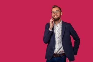 Studio shot of attractive brunette business man with glasses, in casual shirt, stylish black jacket talking on the cell phone and smiling. photo