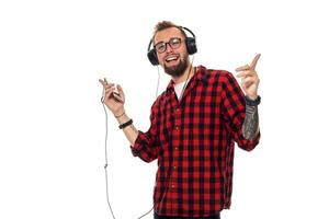 Young hipster man in checkered shirt and glasses wearing earphones looking happy on white background. photo