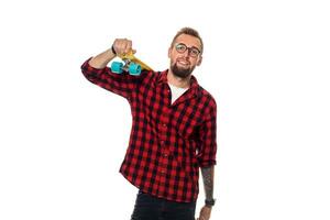 Hipster man over white background holding yellow skateboard. Active guy in plaid shirt with copy space photo