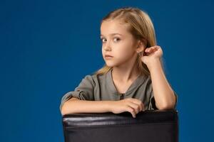 Little girl with gray eyes and blond hair sits on a chair photo