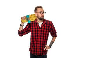 Hipster man over white background holding yellow skateboard. Active guy in plaid shirt with copy space photo