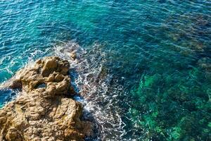 Clear waves of Mediterranean sea hitting the rocks of Marseille photo