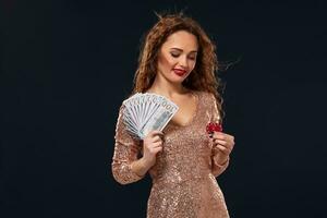 Image of lucky happy woman with brown long hair with fan of 100 dollar bills, lots of cash money, over black background photo