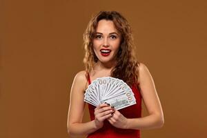imagen de suerte contento mujer con marrón largo pelo con ventilador de 100 dólar facturas, un montón de efectivo dinero, terminado marrón antecedentes foto