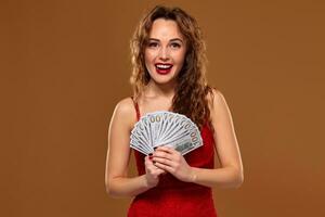 imagen de suerte contento mujer con marrón largo pelo con ventilador de 100 dólar facturas, un montón de efectivo dinero, terminado marrón antecedentes foto