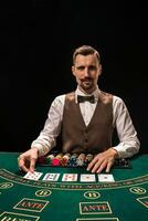 Portrait of a croupier is holding playing cards, gambling chips on table. Black background photo