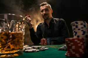 hombre es jugando póker con un cigarro y un whisky. un hombre victorioso todas el papas fritas en el mesa con grueso cigarrillo fumar. foto