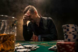 hombre es jugando póker con un cigarro y un whisky. un hombre victorioso todas el papas fritas en el mesa con grueso cigarrillo fumar. foto