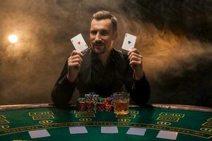 Bearded man showing poker cards on smoke black background photo