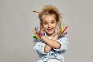 Beautiful little girl with a painted hands is posing on a gray background. photo
