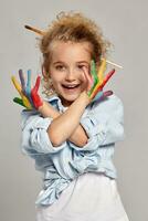 Beautiful little girl with a painted hands is posing on a gray background. photo