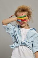 Beautiful little girl with a painted hands is posing on a gray background. photo