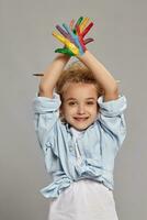 Beautiful little girl with a painted hands is posing on a gray background. photo