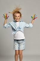 Beautiful little girl with a painted hands and cheeks is posing on a gray background. photo