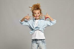 Beautiful little girl with a painted hands and cheeks is posing on a gray background. photo