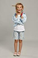 Beautiful little girl with a painted hands and cheeks is posing on a gray background. photo