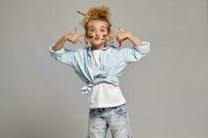 Beautiful little girl with a painted hands and cheeks is posing on a gray background. photo