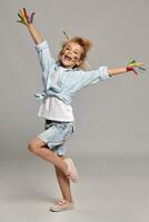 Beautiful little girl with a painted hands and cheeks is posing on a gray background. photo