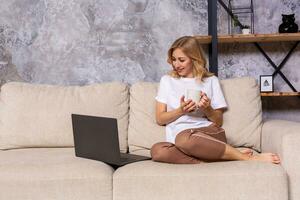 Young beautiful woman using laptop computer smiling happy watching and browsing or doing online internet shopping at home. photo