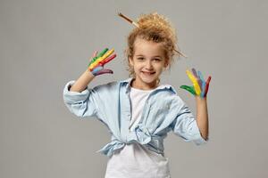 Beautiful little girl with a painted fingers is posing on a gray background. photo