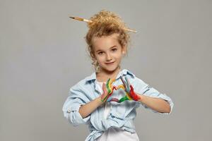 Beautiful little girl with a painted hands is posing on a gray background. photo