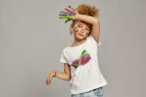 Beautiful little girl with a painted fingers is posing on a gray background. photo