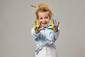 Beautiful little girl with a painted hands is posing on a gray background. photo