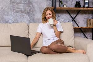 Young beautiful woman using laptop computer smiling happy watching and browsing or doing online internet shopping at home. photo