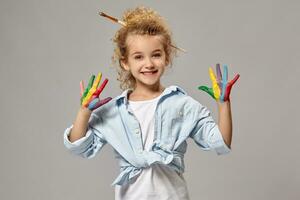 Beautiful little girl with a painted hands is posing on a gray background. photo