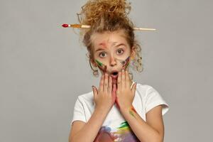 Beautiful little girl with a painted fingers is posing on a gray background. photo