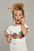 Beautiful little girl with a painted fingers is posing on a gray background. photo